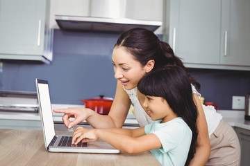 Happy mother and daughter working on laptop 