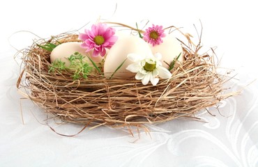 Fototapeta na wymiar Easter white eggs in the nest with pink and white flowers