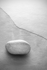 Fototapeta na wymiar Black and white photo of a stone on slate background with copy space.