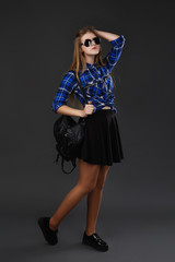 Full-lenght portrait of a girl in a plaid shirt and black skirt
