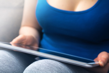 Busty Woman In Blue Tank Top Leaning A Business Tablet On Her Knees