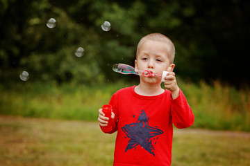Child blowing a soap bubbles. Kid blowing bubbles on nature.
