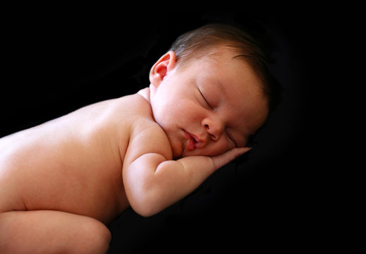 Profile view of a beautiful sleeping newborn baby on a black background