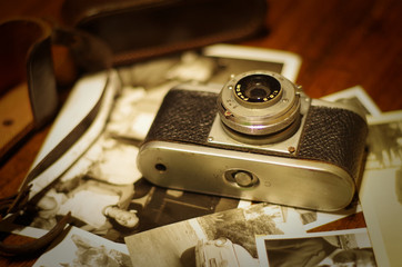 Vintage photo camera with old pictures on wooden table
