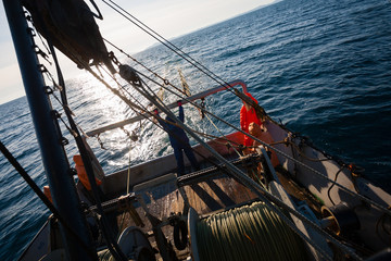 Fishermen standing at the stern of small fishing vessel
