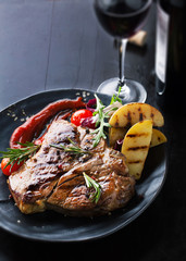 Grilled meat T-Bone with vegetables, spices and glass of wine
