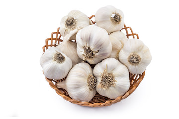 Pile of fresh organic garlic in woven basket isolated on white background