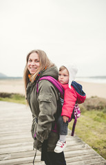 Fototapeta premium Portrait of a mother carrying her child in a backpack