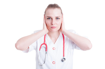 Attractive young woman doctor covering her ears with hands