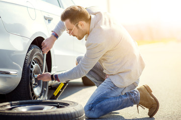 Changing tire on broken car on road