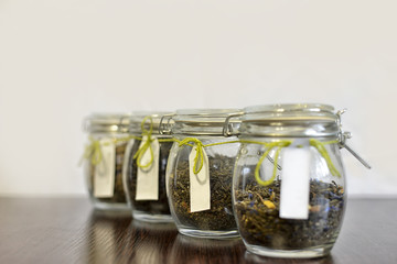 tea in glass jars on wooden table with white background