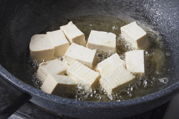 soy bean tofu while frying in pan (vegetarian food)
