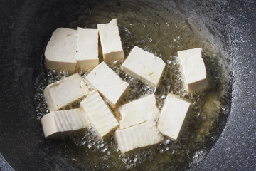 soy bean tofu while frying in pan (vegetarian food)

