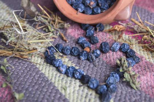 Dried blue berries on colorful ethnic carpet and clay pot.