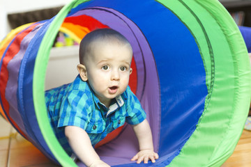 Adorable little boy playing inside a toy tunnel