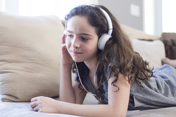 Woman listening music in headphones on sofa in room