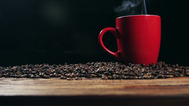cup with hot drink on roasted coffee beans.