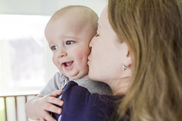 Happy mother with her baby boy at home in bedroom