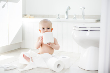 Adorable baby boy playing with toilet paper