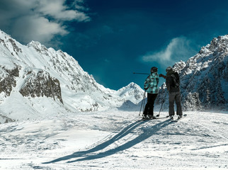 Skiers couple looking on the winter mountains in sun day.