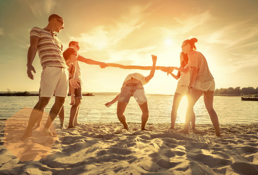 Friends funny game on the beach under sunset sunlight.