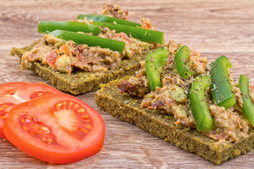 Raw bread with a spread decorated with pepper and tomatoes