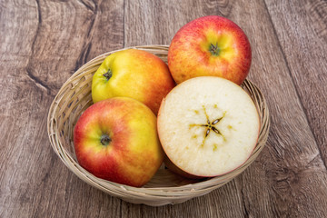 Apples in a knitted bowl on a wooden background