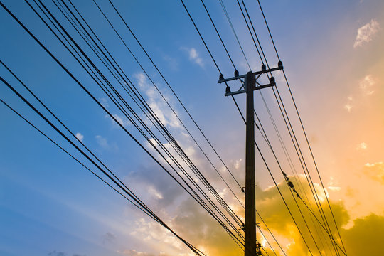 Silhouette, Electricity transmission lines and power poles Sunshine twilight sky backdrop.