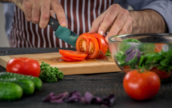 Male hands cutting vegetables for salad