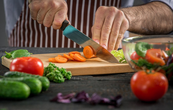 Male hands cutting vegetables for salad