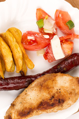 Chicken breasts and grilled red sausages on the plate