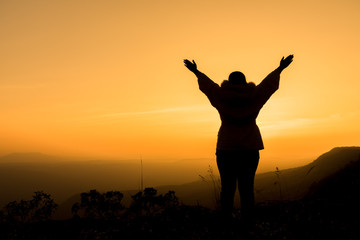woman raising her arms and enjoying the beautiful sunset