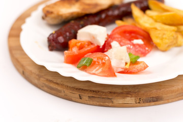 Chicken breasts and grilled red sausages on the plate