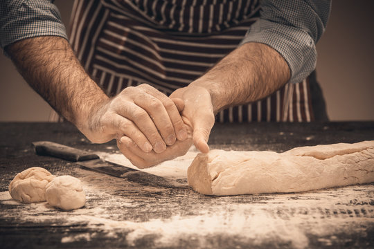 Male hands knead the dough.