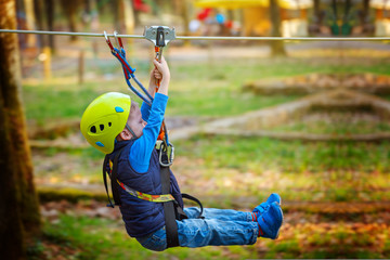 Adventure climbing high wire park - kid on course in  helmet and safety equipment © Volha Zaitsava