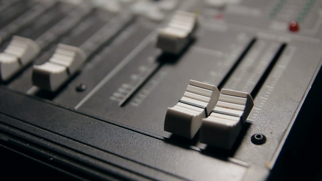 Raising and lowering the volume on a sound mixer.