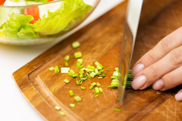 close up of woman chopping green onion with knife