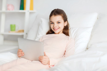 happy girl lying in bed with tablet pc at home