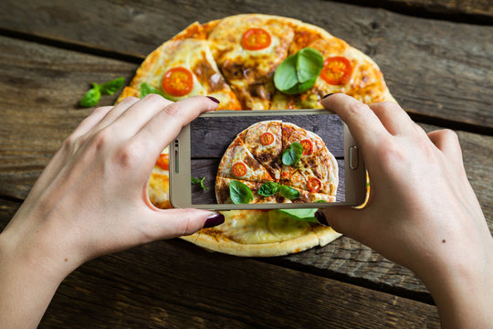Girl photographs pizza on your smartphone