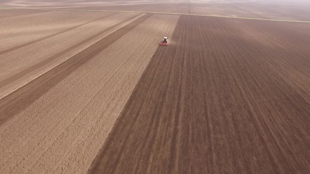 Farmer in tractor preparing land with seedbed cultivator