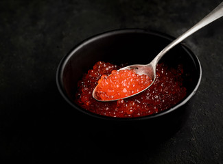 Caviar.spoon with red caviar on a black background
