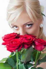 Portrait of a charming bride with beautiful smile and red lipstick, looking up ,with a bouquet of red roses