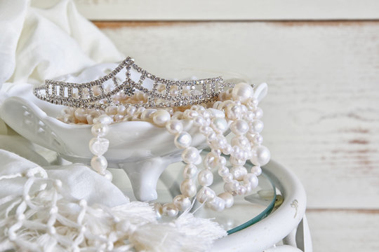 image of white pearls necklace and diamond tiara on vintage table. selective focus
