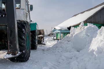 Winter time. Tractor cleans snow in village