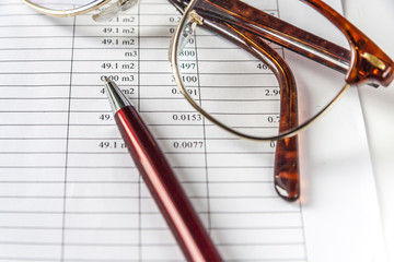 A Pen And Eyeglasses On a Page With Financial Data.