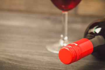 Bottle of red wine and glass on wooden table