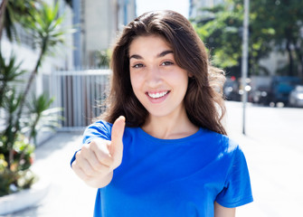 Frau im blauen Shirt in der Stadt zeigt Daumen