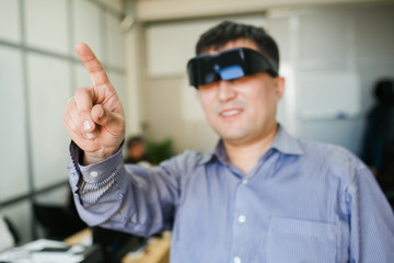 Man in a virtual reality helmet points finger up.