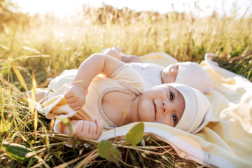Funny twins sisters newborn babies lying on grass in summer day