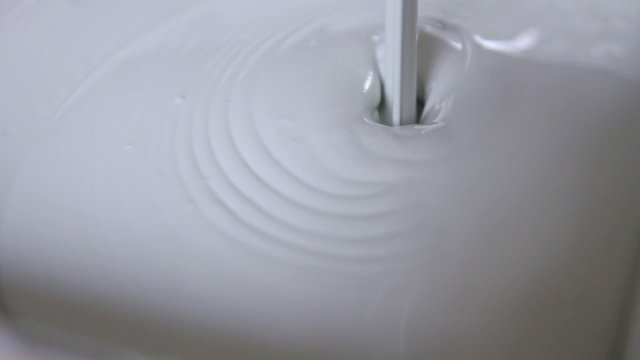 Close up of white paint being poured into a tray.